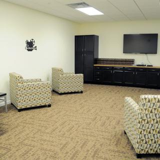A modern office waiting room with patterned chairs and a television.