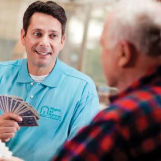 A caregiver playing cards with an elderly person, engaging in a friendly interaction.