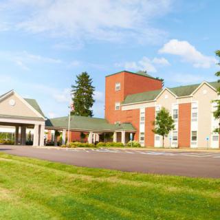 A modern hotel with a brick facade, set against a clear blue sky and surrounded by lush greenery.