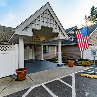 An entrance to a building with an American flag and adjacent parking spaces.