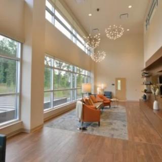 A modern and spacious lobby area featuring large windows, elegant chandeliers, and comfortable seating.