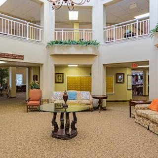 A spacious lobby area featuring sofas, a central round table, and a chandelier above.