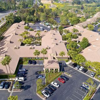 Aerial view of a building complex with a surrounding parking lot and lush greenery.