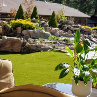A peaceful backyard with lush greenery, a rock garden, and patio furniture.