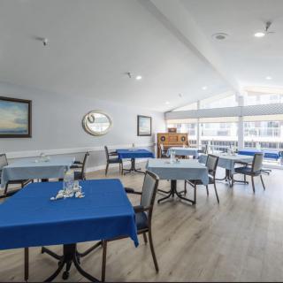A bright dining area with blue tablecloths on the tables, surrounded by large windows.