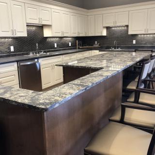 A modern kitchen featuring a large marble island and white cabinets.