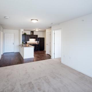 A modern apartment with an open floor plan, featuring a kitchen and living area.
