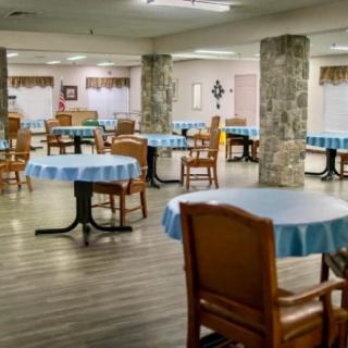 An empty dining area with tables covered in blue tablecloths and wooden chairs.