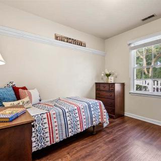 A cozy bedroom with a single bed, colorful bedding, and a window allowing natural light.