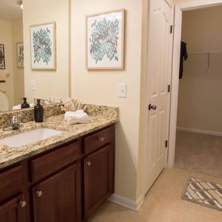 A well-organized bathroom with a granite countertop and decorative artwork.