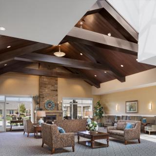 A spacious lobby featuring high wooden beam ceilings, comfortable seating, and large windows providing natural light.