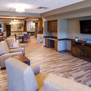 A modern lounge area featuring comfortable seating and a television, with wood flooring and elegant lighting.