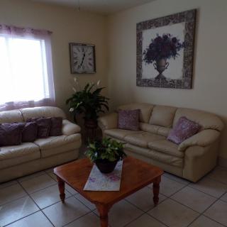 A cozy living room with beige sofas, a wooden coffee table, and decorative elements including an indoor plant and wall art.
