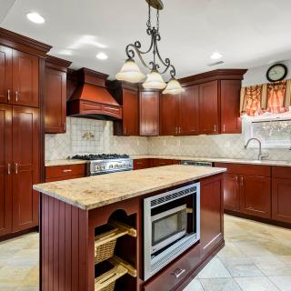 A modern kitchen with wooden cabinets and a granite countertop featuring a central island.