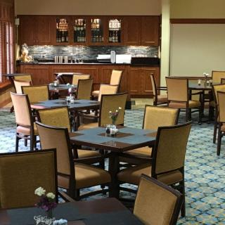A cozy restaurant dining area with several tables and chairs, featuring a coffee station in the background.