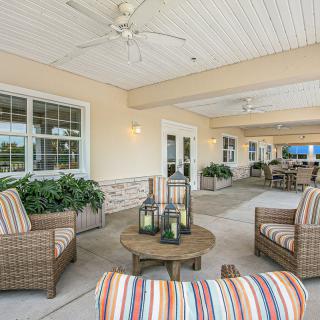 A cozy outdoor patio with wicker furniture, colorful cushions, and decorative lanterns.