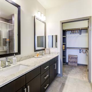A modern bathroom with dual sinks and a walk-in closet.