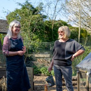 Two women enjoying a conversation in a sunny garden.