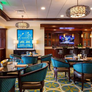 A cozy restaurant interior featuring a dining area with stylish chairs and tables, complemented by elegant lighting and decor.