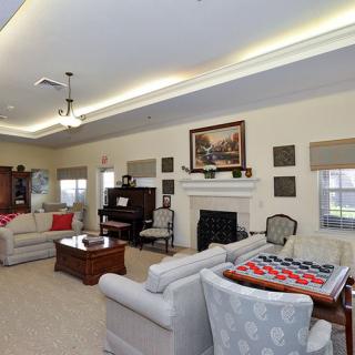 A spacious and elegantly decorated living room featuring a grand piano, a cozy fireplace, and comfortable sofas.