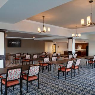 A spacious conference room with rows of chairs and tables, equipped with a projector screen.
