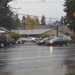A rainy day scene showing cars at an intersection near residential houses.
