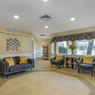 A cozy living room featuring a sofa and chairs with decorative pillows, large windows, and tasteful decor.