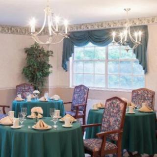 A formal dining room with elegantly set tables and upholstered chairs.