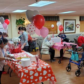 A festive gathering celebrating Valentine's Day at a community center for seniors.