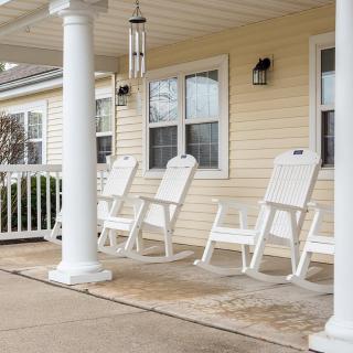 A cozy porch with white rocking chairs and sturdy columns.