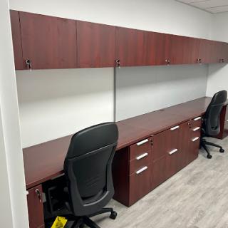 A modern office setup featuring wooden desks and ergonomic chairs.