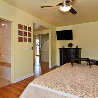 A cozy bedroom with a ceiling fan and a wall-mounted television.
