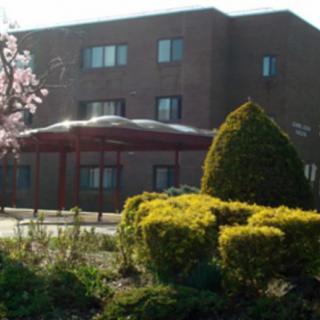 A brick building with landscaped gardens and blooming trees in the foreground.