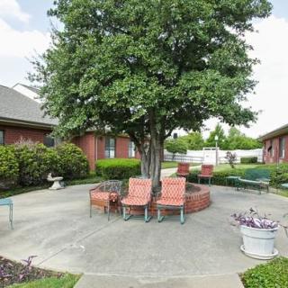 A tranquil courtyard with a large tree and outdoor seating surrounded by brick buildings.