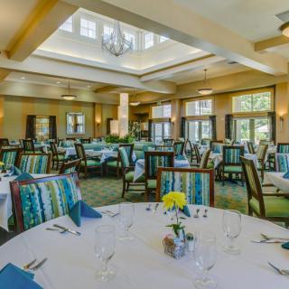 An elegant dining hall set up with round tables and neatly arranged chairs, ready for guests.