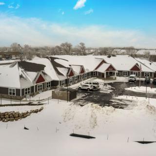 A snowy landscape with a series of buildings and a parking lot under a clear blue sky.