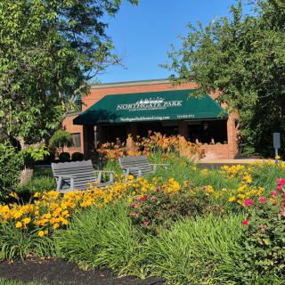 A beautifully landscaped garden with colorful flowers in front of a building featuring a green awning.