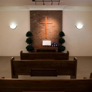 Interior view of a church with wooden pews and a cross on the wall.