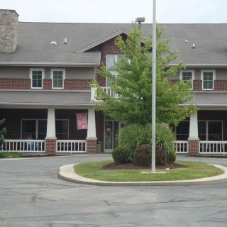A two-story commercial brick building with a porch and adjacent parking area.