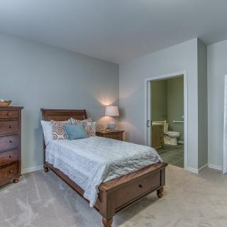 A cozy bedroom with a single bed, wooden furniture, and soft lighting.