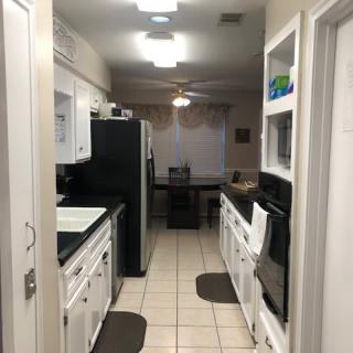 A modern kitchen with white cabinets, black appliances, and tiled flooring.