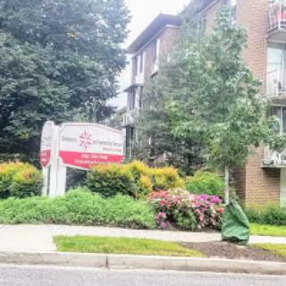 A view of a residential apartment complex surrounded by lush greenery and colorful flowers.