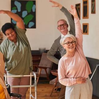A group of seniors engaging in a stretching exercise together indoors.