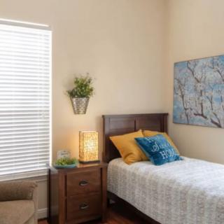 A cozy bedroom with a single bed, decorative pillows, and a nightstand under a piece of wall art.