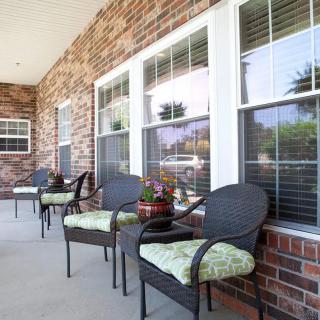 A cozy porch with wicker chairs and a brick wall backdrop.