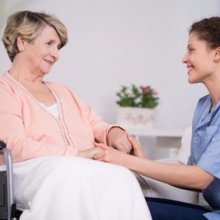 A nurse providing care and support to an elderly woman in a wheelchair.