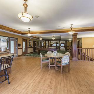 A spacious living area featuring wood flooring, chandeliers, and comfortable seating.