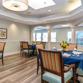 A bright and elegant dining room with neatly arranged tables and chairs, complemented by modern lighting and decor.