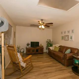 A cozy living room featuring a comfortable couch, a rocking chair, and a television, set against warm wooden flooring.