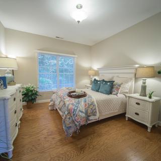 A cozy bedroom with a neatly made bed, wooden floors, and elegant decor.